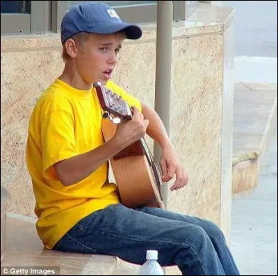 Devant quel b&acirc;timent Justin jouait-il de la guitare, pour gagner des sous ?