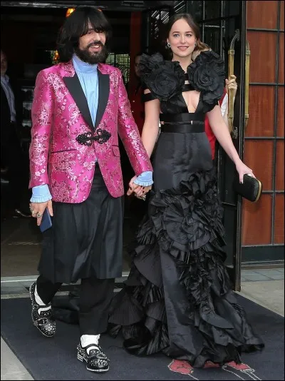 La jeune femme est l'actrice Dakota Johnson (Fifty shades of Grey), fille de Mélanie Griffiths et de Don Johnson (Miami Vice) qui porte une belle robe signée Gucci. Mais à ses côtés, il y a l'impensable en matière de tenue. A votre avis, qui est ce monsieur ainsi vêtu ?