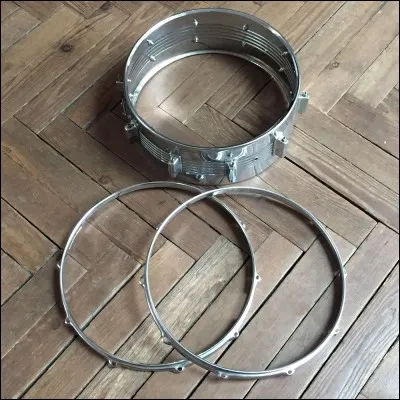 Comment se nomme la partie métallique au bord d'une percussion en batterie ?