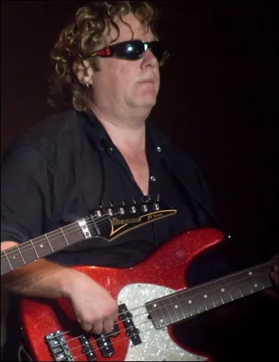 Qui est ce bassiste américain connu pour jouer avec de grands artistes (Joe Satriani, entre autres), ainsi que pour ses enregistrements en solo et ses talents de composition dans plusieurs styles différents (fusion, country, musique classique) ?