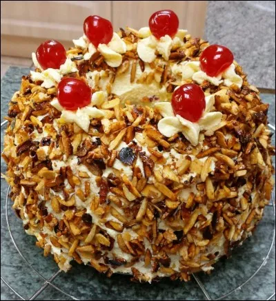 Ce gâteau, en forme d'anneau, enrobé de croquant doré et surmonté de cerises confites rubis est l'emblème d'une ville de couronnements. Laquelle ?