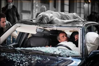 Quelle est la couleur de la robe de la demoiselle qui s'écrase sur la voiture du commandant ?