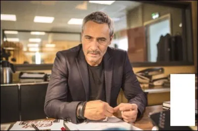 Qu'est-ce qui est posé sur le bureau de Fred, devant lui ?