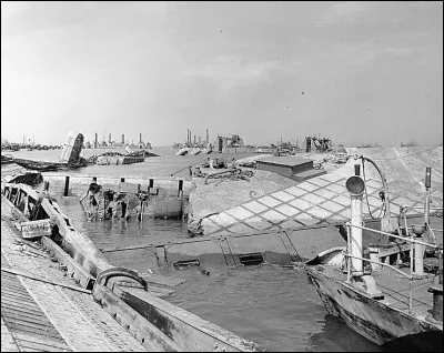 2 ports artificiels (Mulberry A et Mulberry B) ont été construits en Angleterre puis posés sur les plages du Débarquement.
Le port Mulberry A a été détruit entre le 19 et le 21 juin 1944.
Comment a-t-il été détruit ?