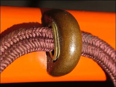 Sur le fourreau, le passant par lequel passe la cordelette se nomme :