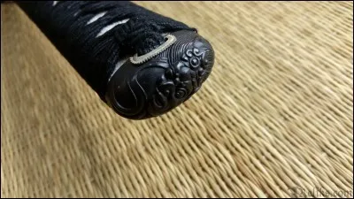 Comment appelle-t-on le bout décoré du pommeau (de la poignée) ?