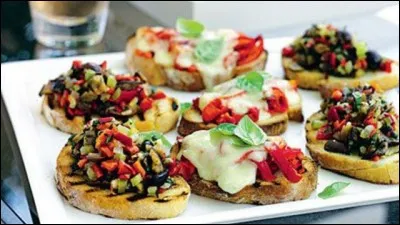 Préparation culinaire traditionnelle d'antipasti. Il s'agit traditionnellement d'une tartine de pain de campagne, rassis ou grillé, frotté à l'ail, assaisonné d'huile d'olive, garnie de petits morceaux de tomates séchées, assaisonnée de feuilles de basilic, avec parfois poivrons grillés, olives, pesto, anchois, vinaigre balsamique.