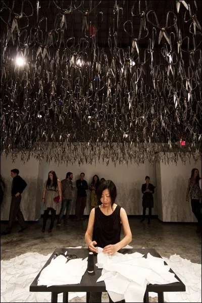 Cette jeune femme est assise sous des dizaines de grands ciseaux suspendus pointes en bas.... par goût du risque ? Pour quelle raison ?