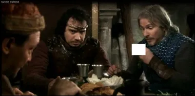 Dans cette scène, celle du repas avec les Maures, qu'est-ce que Perceval est en train de porter à sa bouche ?