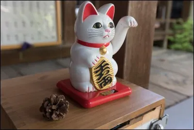 Ce chat porte-bonheur japonais lève la patte gauche en signe de bienvenue. Son nom est...