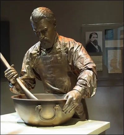 C'était un pharmacien, titre un peu relatif à l'époque, un peu apothicaire comme on le voit représenté avec son creuset et son pilon. Il a mis au point une recette qui est devenu un breuvage mondialement célèbre. Était-ce un remède ? On le voit ici au musée de l'usine-mère. C'est :