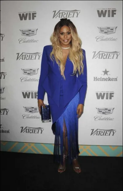 Laverne Cox, actrice, s'est ainsi habillée pour la cérémonie des Emmys. Cette coupe en biais bordée de longues franges, sans compter les paddings, est hideuse. Quelle fut l'époque des sacs de daim à franges en France ?