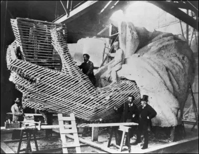 On voit ici Bartholdi expliquant le détail de la main. Il était déjà le sculpteur de la Fontaine de Bartholdi à Washington et de la Statue de Lafayette, à New York. 
Cette photo montre la structure en bois fabriquée à partir de liteaux utilisés pour le moulage en plâtre de la main de la statue, celle qui tient la tablette. 
Qu'est-ce que cela donne une fois le plâtre cassé et le bois enlevé ?