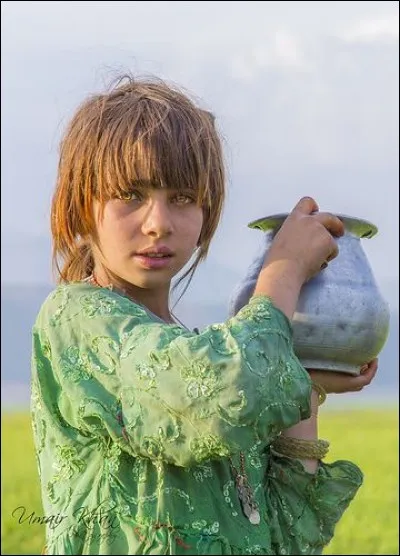 C'est un magnifique cliché d'Umair Khan. Il s'agit de la ''Fille d'un berger'' prenant le pot d'eau pour son père. Le photographe commente : ''La couleur de ses yeux est tout naturel''. Ce sont des Aryens antiques qui vivent dans le nord du pays et ''peuplent des villages où la propreté de leurs maisons et la pureté de leurs moeurs tranchent sur leurs voisins''.
De quelle communauté est-elle ?