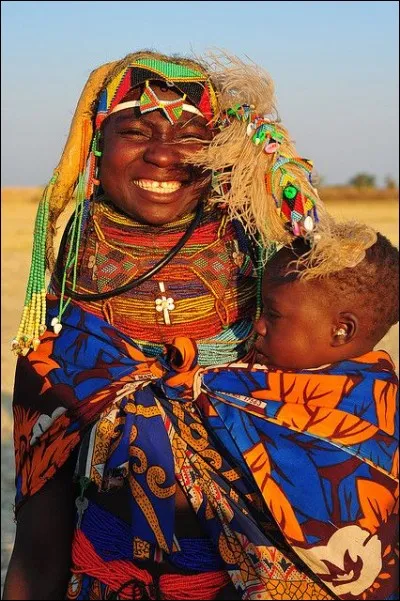 L. Gargano a capté cette mère et son fils semi-nomades de la région de Huila. Elle fait partie d'un des 1ers peuples bantous à entreprendre la migration vers le sud du continent. L'agriculture y est de subsistance et ils ont quelques poules, chèvres et bovins.
Situez ces gens qui ont une façon unique d'habiller leur robe avec des ornements, portant une coiffure qui a un sens culturel important ?