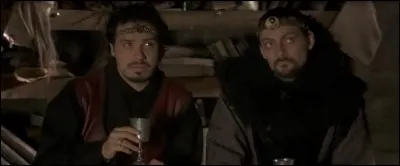 Lors de la scène où Merlin récite des blagues pour le 2e Rassemblement du corbeau, à quel doigt de la main droite Elias porte-t-il une bague ?