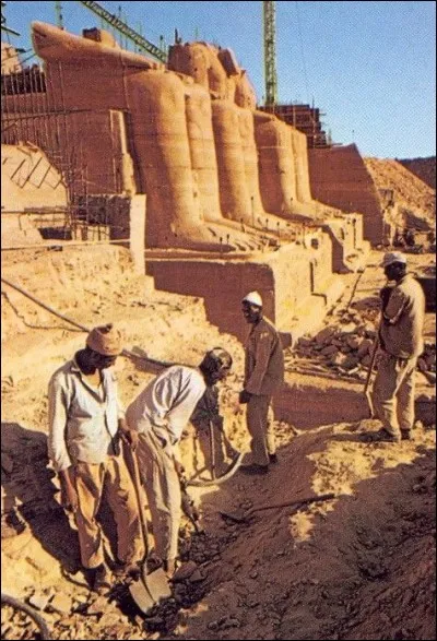 Il fallut aussi créer des collines artificielles, reproduisant les collines d'origine, avant de remettre les blocs : ces collines serviront à coiffer les sanctuaires et les tiendront à l'abri de la montée des eaux.
Ici, on voit les ouvriers au travail au pied de la falaise nouvellement reconstituée et devant le temple, qui ne l'est, lui, que partiellement.

Sommairement, ils en sont :