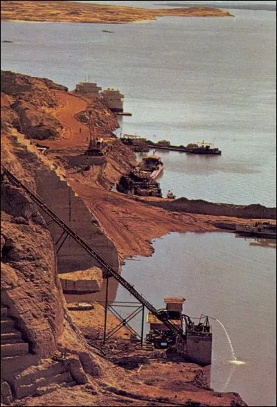 Le projet du barrage d'Assouan du Président Nasser avait entrainé la formation d'un immense lac artificiel menaçant d'immerger les temples : il fallut les déplacer plus haut. 
On érigea un batardeau pour retarder l'avancement des eaux, le temps de transporter tous les matériaux.
 
Que sont-ils en train de faire sur la photo ?