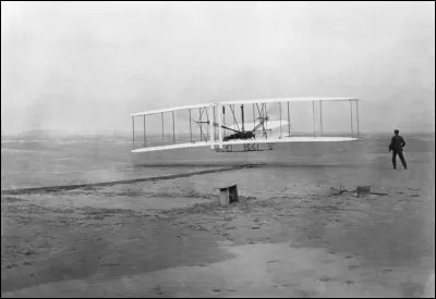 Photo prise dans les dunes de Kitty Hawk : il s'agit du 1er vol pour un être humain sur un engin de sa conception, motorisé mécaniquement.
Le 1er vol à moteur contrôlé et prolongé. ''Orville Wright était aux commandes et Wilbur Wright courait sur le côté pour équilibrer l'avion. Sur la photo, il vient de lâcher la barre avant de l'aile droite de l'appareil.''
Quelle est l'année de cet exploit ?