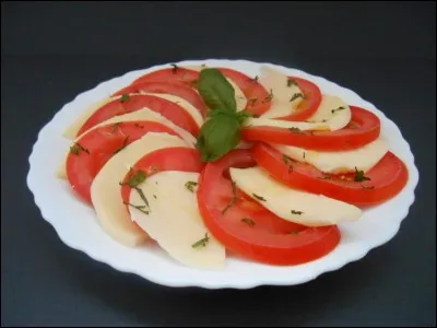 Je n'ai pas pu résister à vous servir encore ce genre d'entrée : voici une assiette de tomates mozzarella. Quelle herbe aromatique l'accompagne, et lui est indissociable ?