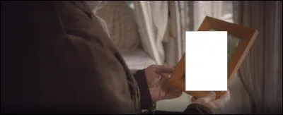 Avant de le ranger, le mari regarde un cadre qui contient une photo de...