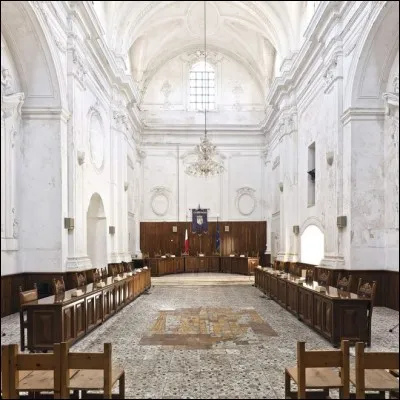 Le photographe A. Di Martino parcourt l'Italie à la recherche d'églises déconsacrées : ses photos, intitulées «La messe est finie», témoignent de l'appauvrissement et de la sécularisation de l'Église. On voit ici la seconde vie de la vieille église Santa Filomena : c'est sous ces volumes imposants que se tient le conseil municipal.
Veillez préciser le conseil municipal de quelle ville.