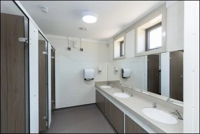 Maintenant, visitons l'extérieur. Dans un coin du bâtiment, se trouvent les toilettes. Combien de WC voyez-vous ?