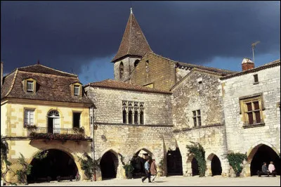 Dans quel village peut-on trouver une place carr&eacute;e bord&eacute;e de maisons en pierres avec arcades ?
