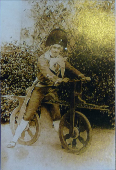 Photo de Camille Bollée en 1910 : archives Bollée/Maine-Découvertes.''Peut-être le plus original de la famille et certainement le plus facétieux, c'est sans doute avec un peu d'ironie et assurément beaucoup d'humour qu'il construisit, à son tour, un 2 roues''. En 1888, il paradait coiffé d'un bicorne, sur ce vélo par lui conçu mais obsolète puisqu'inventé en 1817.
Que conduit Camille Bollée ?