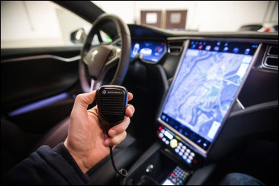 À l'intérieur du véhicule, ce tableau de bord au niveau des policiers dispose d'un GPS, donne l'heure, contrôle les lumières et la sirène ainsi que le LAPI, permet de recevoir des informations par le central. Mais quel est l'objet que tient un policier ?