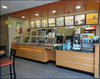 En face, se trouve un petit fast-food où vous pouvez acheter quelque chose à grignoter avant votre vol. Combien de tableaux affichant les menus apercevez-vous ?