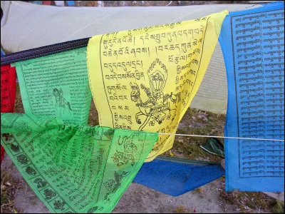 Que symbolise la couleur verte des drapeaux de prières des régions bouddhistes ?