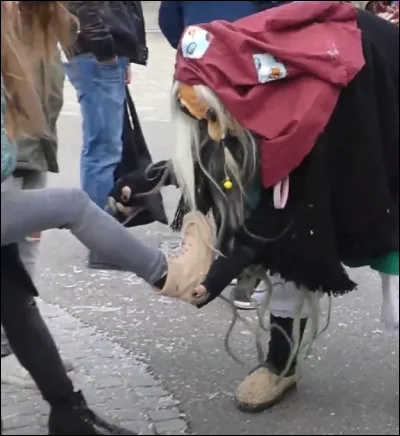 Dans ce carnaval en Allemagne, cette sorcière tente de retirer la chaussure d'une spectatrice. Quelle est la couleur de sa socquette ?