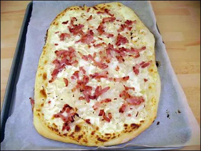 Quelle est la traduction de Flammekueche, plat traditionnel alsacien qui ressemble à une pizza sans tomates mais avec crème fraîche, oignons et lardons ?