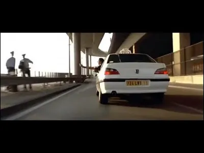 Que fait Daniel quand il dit ''Photo photo'' et que les flics le sifflent quand il conduit Émilien ?