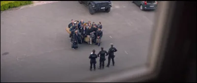 Dans cette sc&egrave;ne du film "RAID Dingue", qui regarde les nouvelles recrues depuis la fen&ecirc;tre ?