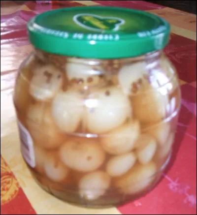Quel est ce condiment, un petit oignon confit au vinaigre et que l'on trouve aussi associé aux cornichons ?
