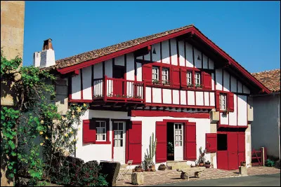 Parmi les diverses maisons basques, les plus caractéristiques se distinguent par leur structure de pierres (recouvertes d'un crépi blanc) et de bois (souvent en rouge basque) avec un toit à double pente peu incliné perpendiculaire à la façade. Comment dénomme-t-on ce type d'habitation propre au Pays basque ?