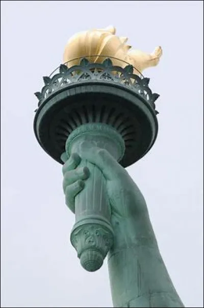 Que signifie la torche qui se trouve dans la main droite de la statue ?