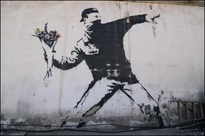 Qui est l'auteur de cette oeuvre intitulée ''Love is in the Air'' où l'on voit un jeune homme lancer un bouquet de fleurs en guise de projectile ?