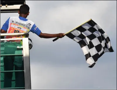 Que signale l'agitation du drapeau noir et blanc à damiers dans les courses automobiles de Formule 1 ?