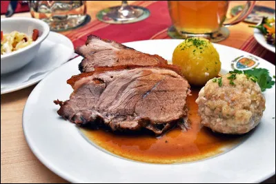 Quel est ce plat principal à base de porc braisé, qui est généralement accompagné de pommes de terre et d'autres légumes qui ont été cuits au four dans le jus de la viande ?