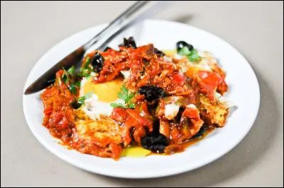 Il y a ici des amateurs d'&oelig;ufs et de tomates ! Présentons une chakchouka, plat de la gastronomie maghrébine.
Imaginons que vous salivez devant l'assiette mais avant de déguster que faut-il verser* dessus pour en améliorer les arômes et saveurs ?