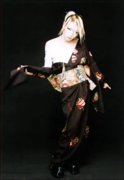 Quel est le nom de ce guitariste et dans quel groupe joue-t-il (sa tenue vestimentaire vous donne un indice) ?