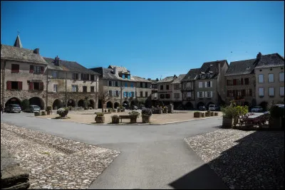 Quel est ce village, ancienne bastide dont la place centrale conserve les allées couvertes ?