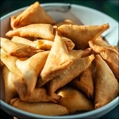 Quel beignet asiatique de forme triangulaire est traditionnellement épicé au piment, à la coriandre ou au curcuma ?