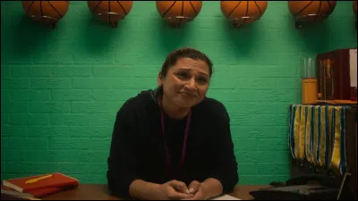 De quelle couleur sont les pots à crayons sur le bureau du coach ?