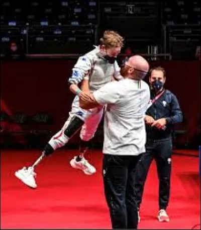 Quel membre de sa famille a participé à l'élaboration de ses prothèses qui lui permettent de tenir son arme ?