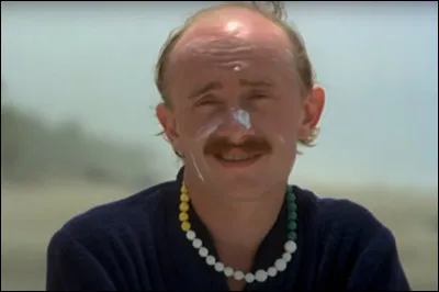 De quel instrument Jean-Claude joue-t-il autour du feu de camp sur la plage ?