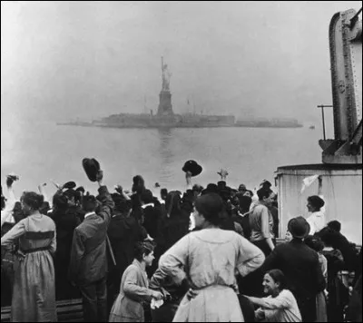 À quelle époque est-elle le symbole de la liberté pour les migrants qui arrivent en bateau à New York ?